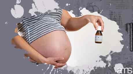 Pregnant woman holds a small bottle of CBD
