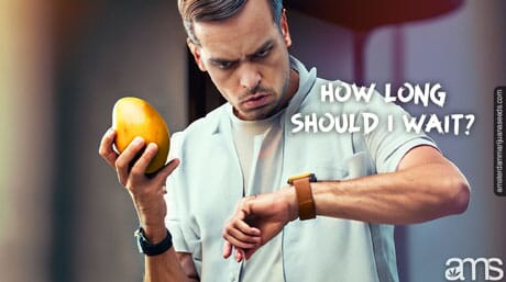 a man with a mango in his hand observes his wristwatch